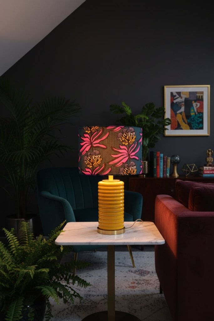 Abajur Protea - Domus Concept - Light StudioAbajurDomus ConceptAbajur Protea Domus Concept - Light Studio cilíndrico com padrão floral vibrante em fundo escuro e interior branco.TamborAbajur de Mesa
